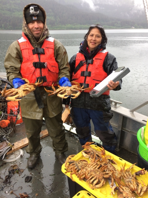Two people holding crabs on a boat.