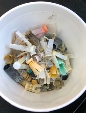 A white, five gallon bucket holds several plastic shotgun wads.