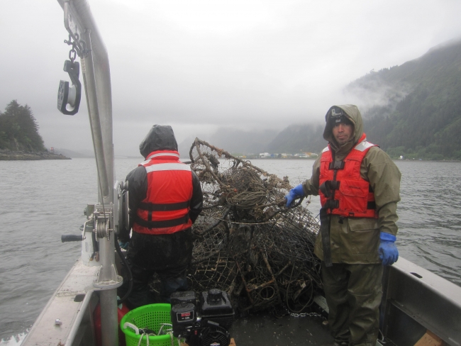 Two people on a boat standing next to derelict crab pots.