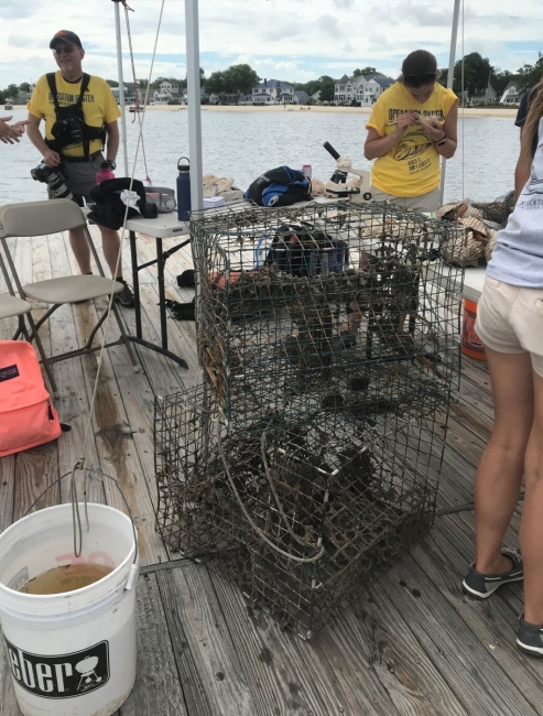 People stand under a tent while they stack crab pots.