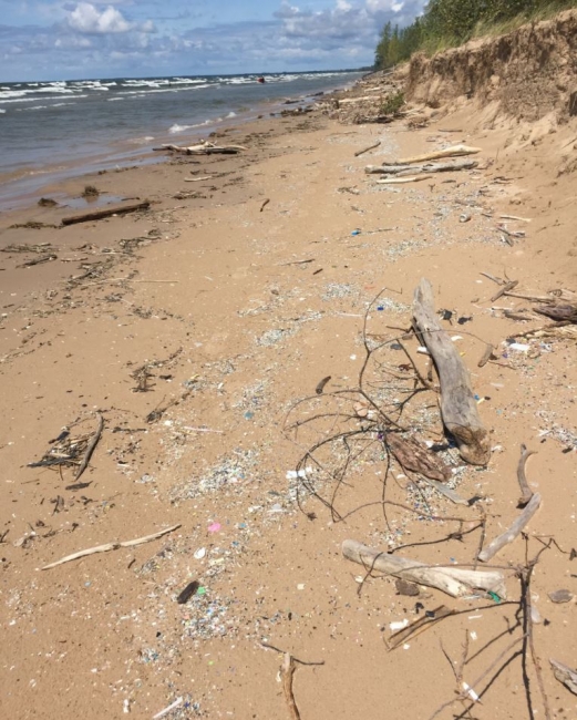 A look down a beach scattered with microplastic debris.