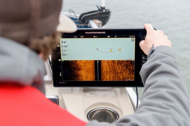 A person on a boat looking at a tablet screen that shows the location of crab pots.