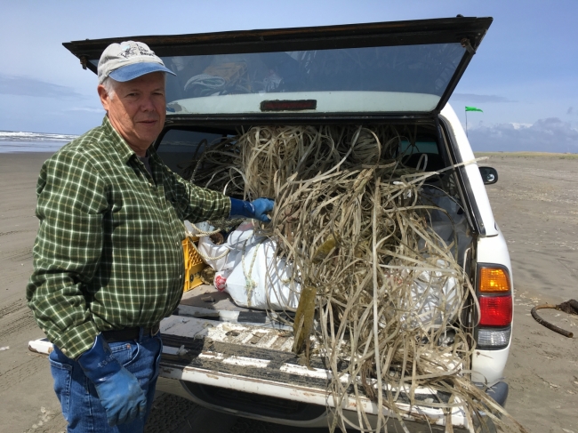 A person stands next to a truck bed filled with debris.