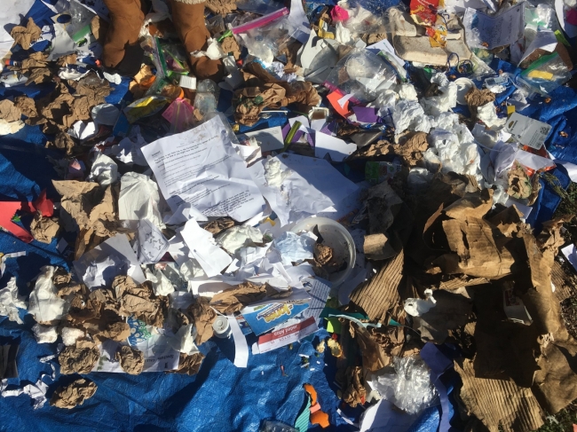 Assorted paper, cardboard, and plastic trash collected from elementary trash bins.