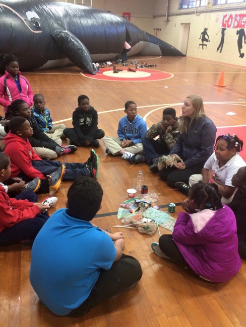 Students sit on the floor with the inflatable whale in the background.