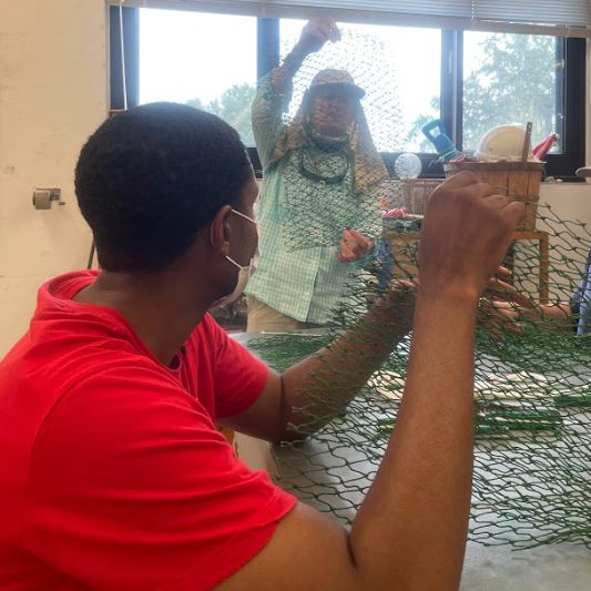 A student learning how to make a cleanup bag from old shrimp nets.