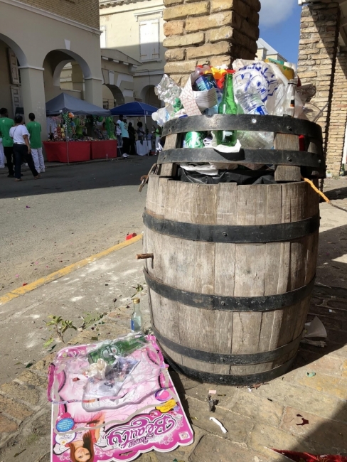 Trash overflowing from a barrel trash can.
