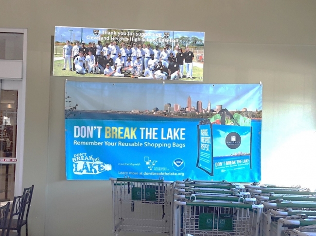 A sign behind shopping carts reading "Don't Break the Lake Remember You Reusable Shopping Bags".