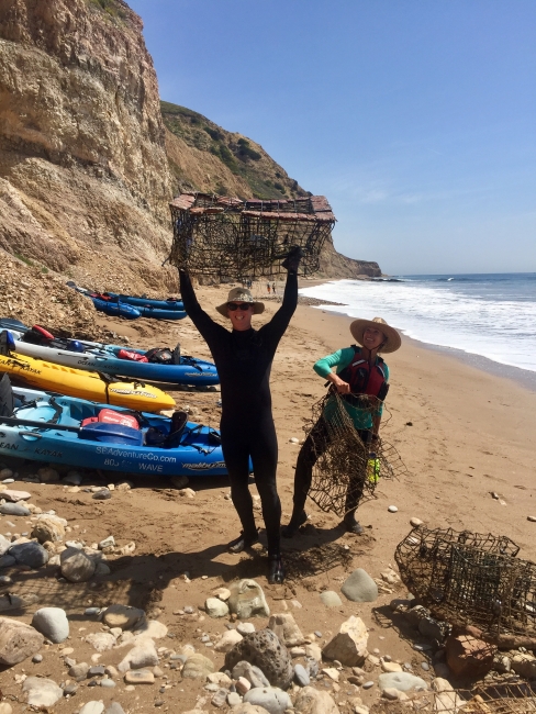 People holding derelict lobster traps on a beach.