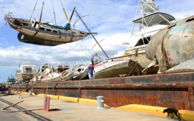 A small boat is being lifted by a barge and loaded on its deck.