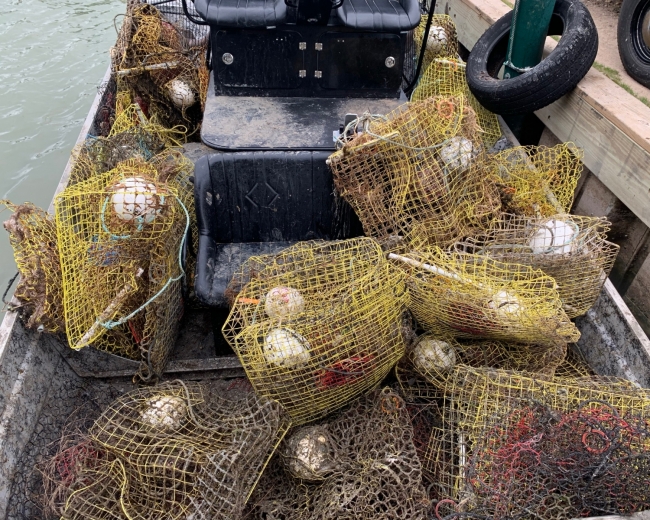 A pile of abandoned crab traps in the back of a boat at a dock.