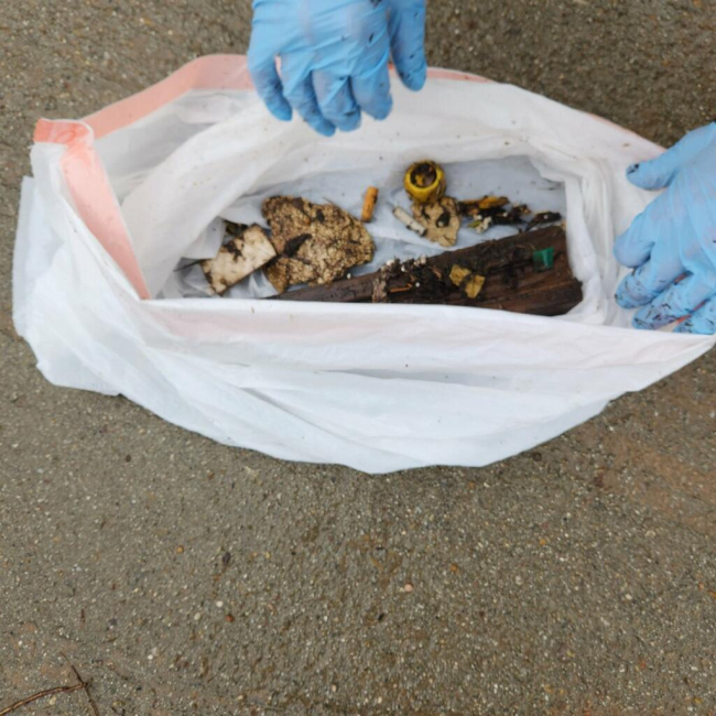 A plastic bag with different pieces of trash. 