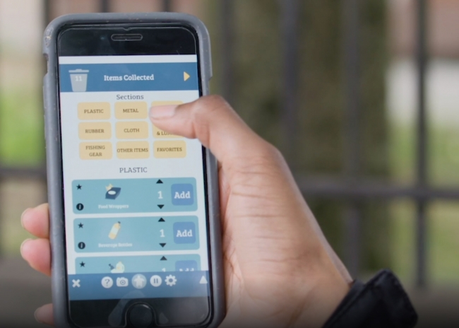 A hand holding up an iPhone with the Marine Tracker app displayed on the screen.