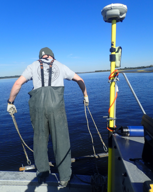 A staff member holding up a custom tool called “The Retriever” that is used to pull up and remove derelict crab traps.