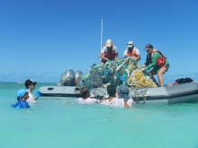 People in a small boat and in the water hauling derelict nets into the boat.