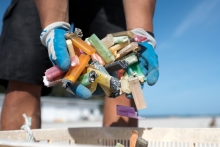 A man dumps several colorful cigarette lighters into a collection tub.