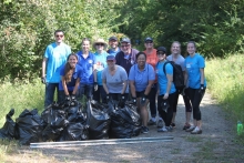 Volunteers stand behind several full garbage bags of collected debris.