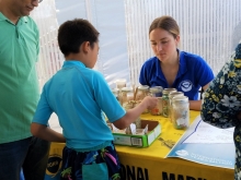 Three people sift through sand with a spoon while trying to avoid collecting microplastics. 