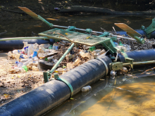 A trash trap device placed in a river that collected plastic water bottles and a tire, preventing the marine debris from moving to other areas.