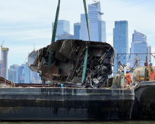 An old, damaged boat getting removed from the water and onto a salvage vessel.