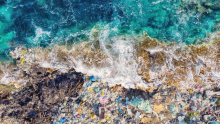 A wave crashing on shore into a pile of marine debris (Photo: Parilov via Adobe Stock).