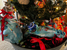 Presents wrapped in pillowcases and ribbon underneath a Christmas tree.