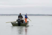 Two people search for derelict crab traps to remove.