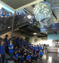 Students standing under a large, hanging whale sculpture.