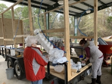 Two people attache plastic bottles to a frame of a parade float located in Louisiana.