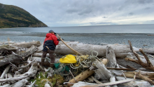 A volunteer removes a net and other marine debris from the shore.