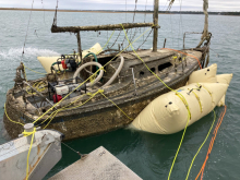 An old abandoned vessel getting lifted with large floats during a removal operation.