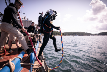 A SCUBA diver jumps off of the boat into the water.