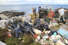 Plastic bags, fishing traps, buoys, and other debris piled up on a shoreline of Eastern Egg Rock, Maine.