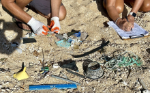 Volunteers sorting through various marine debris items on a sandy shoreline.