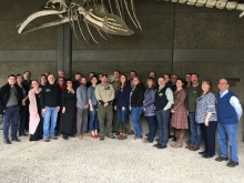 People stand for a photo under a hanging whale skeleton.