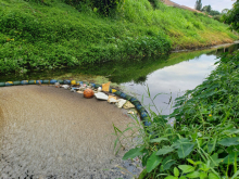 A trash trap device placed in a river that has collected marine debris and prevented it from moving into other areas.