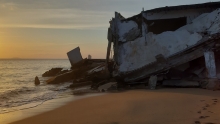 A collapsed structure on an ocean beach shoreline.