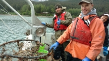 Two people on a boat with a derelict crab pot.