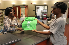 A woman handing a young woman a reusable tote bag.