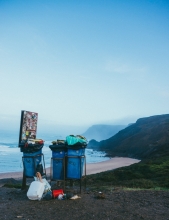 Overflowing recycling bins on a beach. 