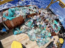 The marine debris removal team atop large piles of removed fishing nets.