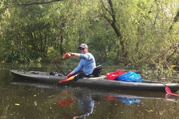 A volunteer in a kayak with debris.
