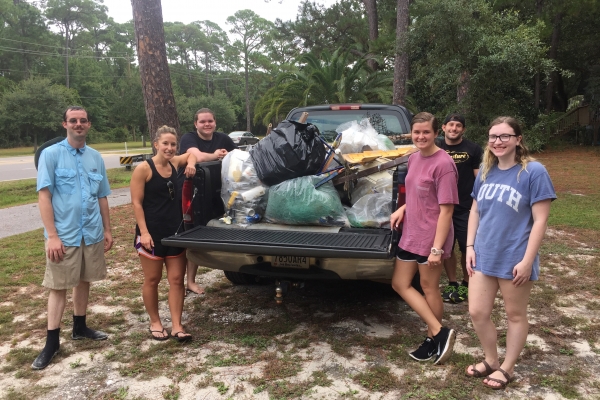 People standing by a truck with garbage bags in the back.